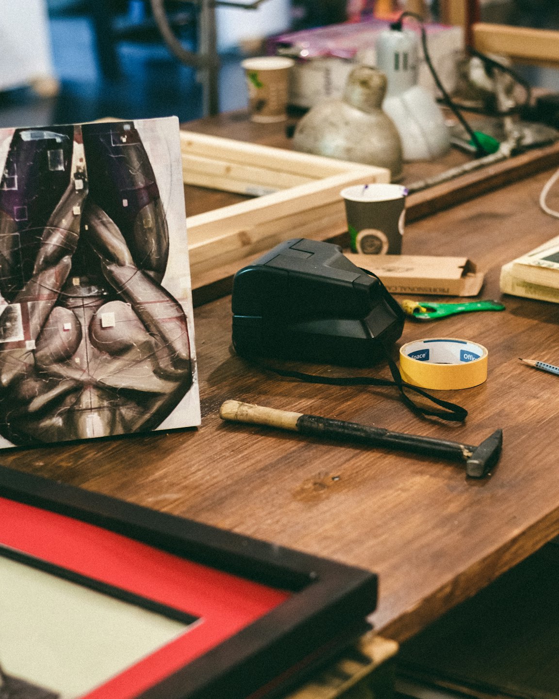 Art supplies and tools are scattered across a wooden workbench.