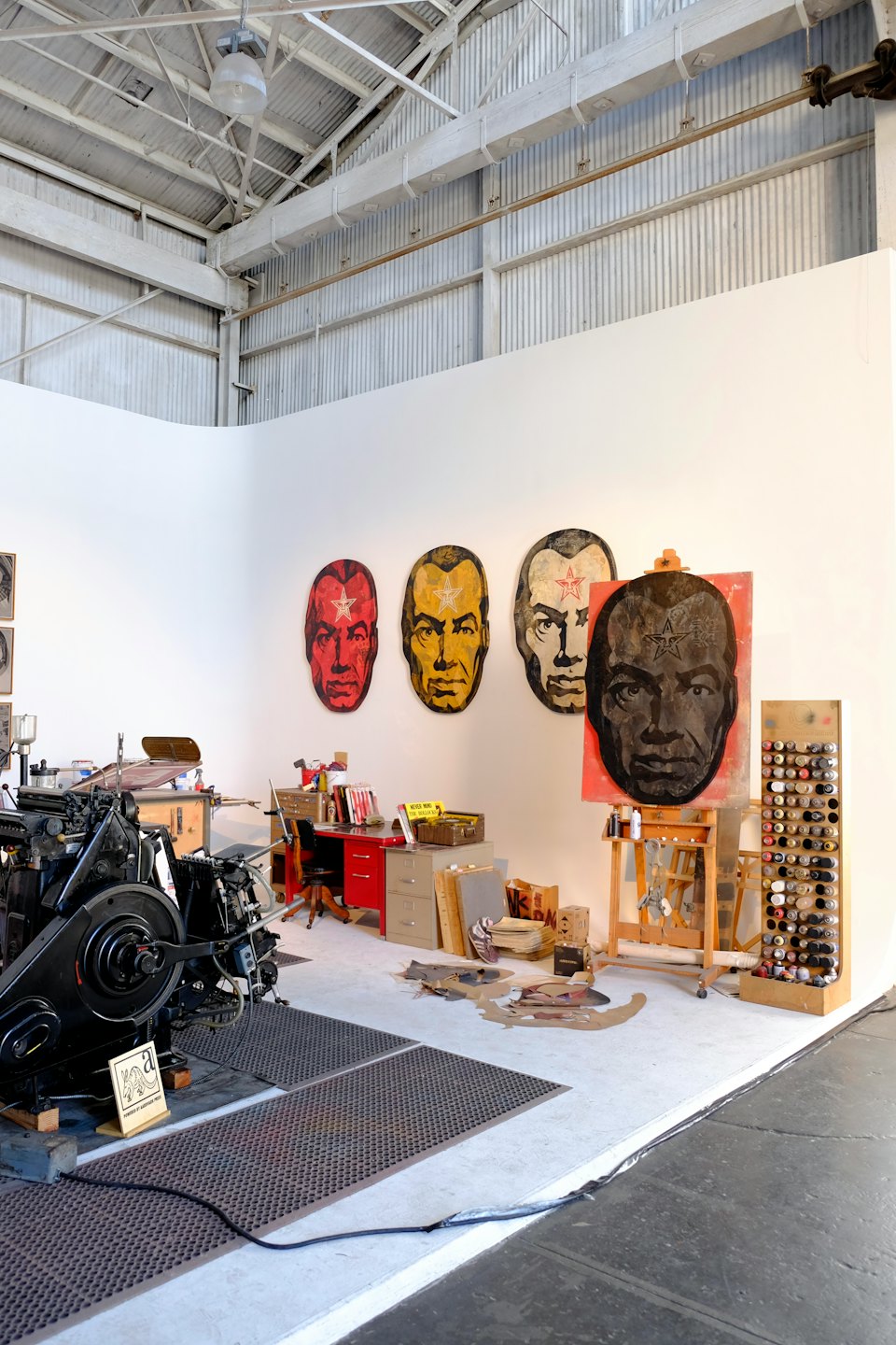 Black industrial printing press stands inside a creative art studio.