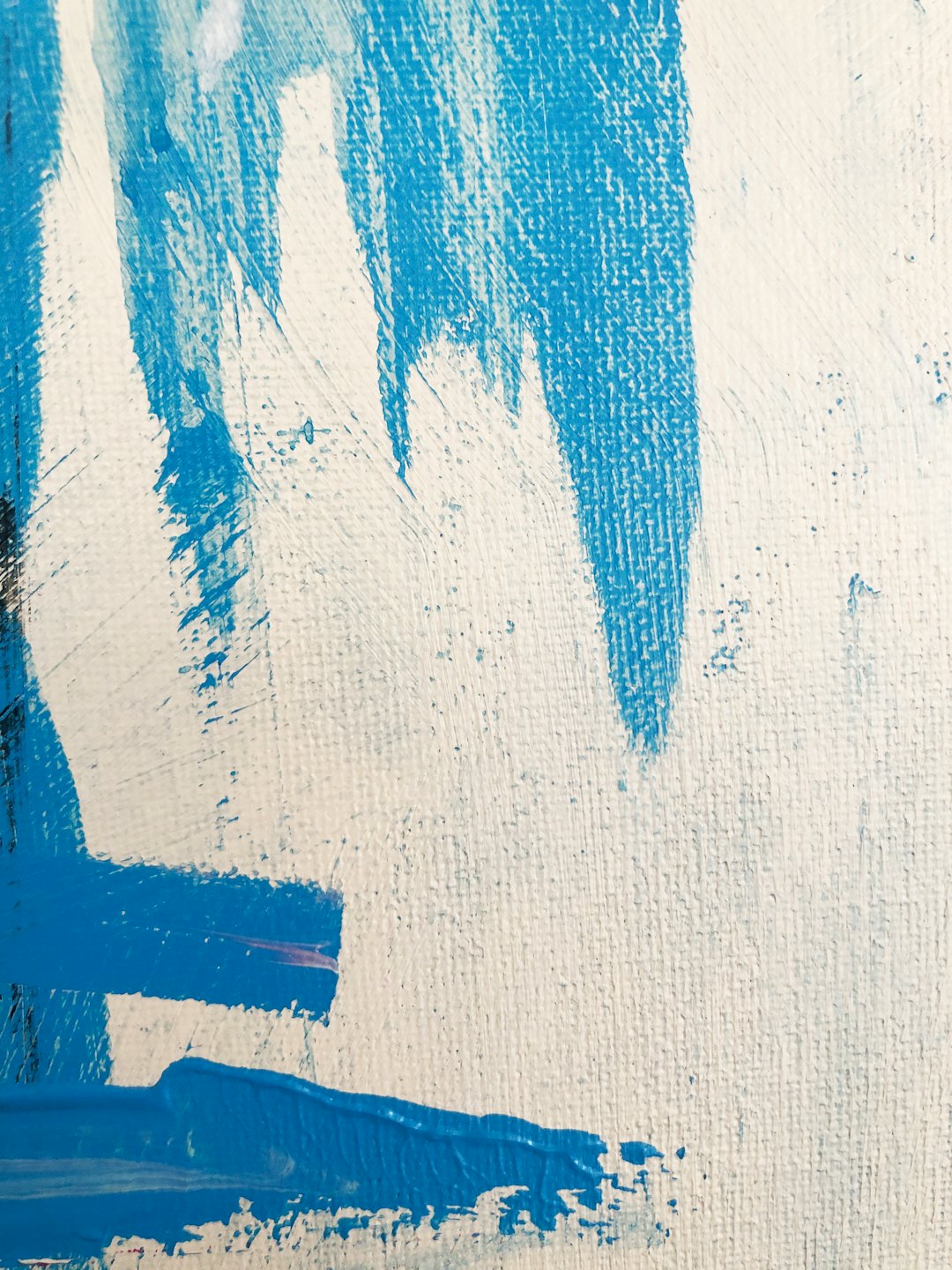 Blue paint applied in bold strokes on a textured canvas.