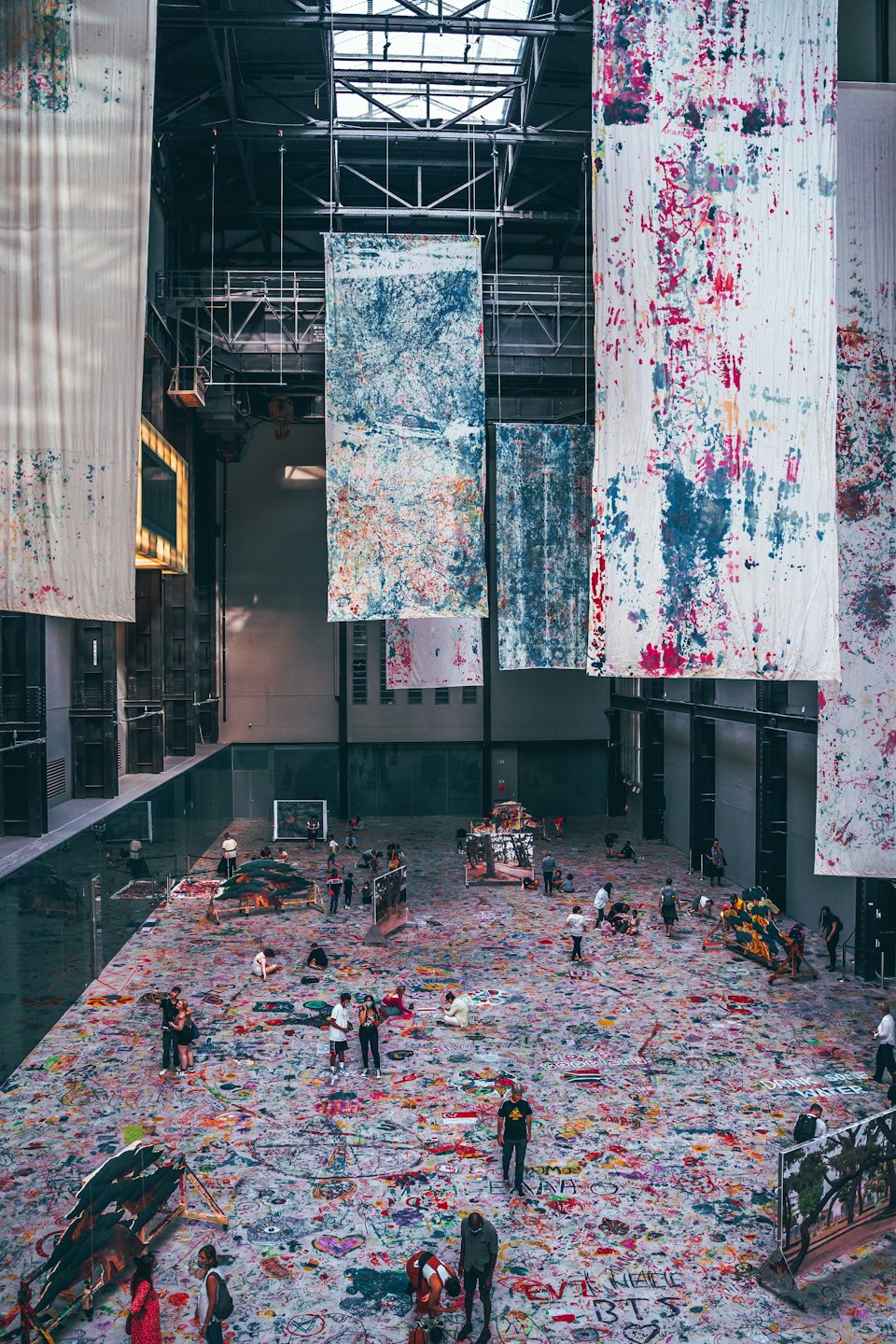 Diverse people interact with a large, colorful art installation in a gallery.